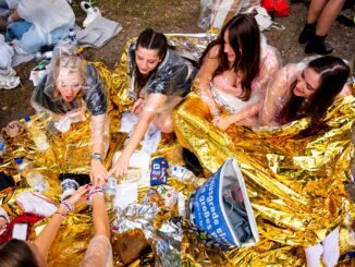 Fans der Sängerin Taylor Swift warten vor dem Konzert im Volksparkstadion mit Kleidung zum Schutz gegen Regen auf den Einlass.