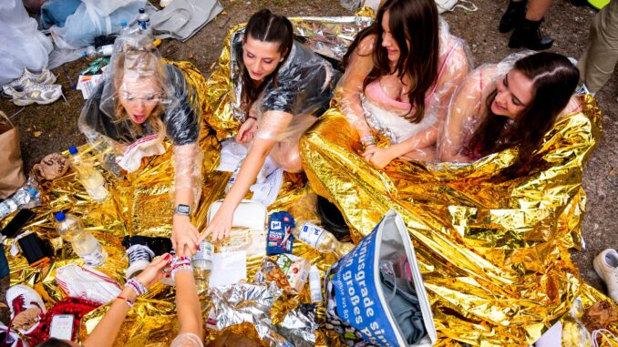 Fans der Sängerin Taylor Swift warten vor dem Konzert im Volksparkstadion mit Kleidung zum Schutz gegen Regen auf den Einlass.