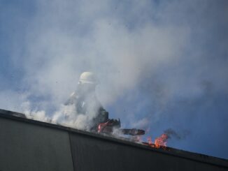 Flammen schlagen aus dem Dach eines viergeschossigen Wohnhauses.