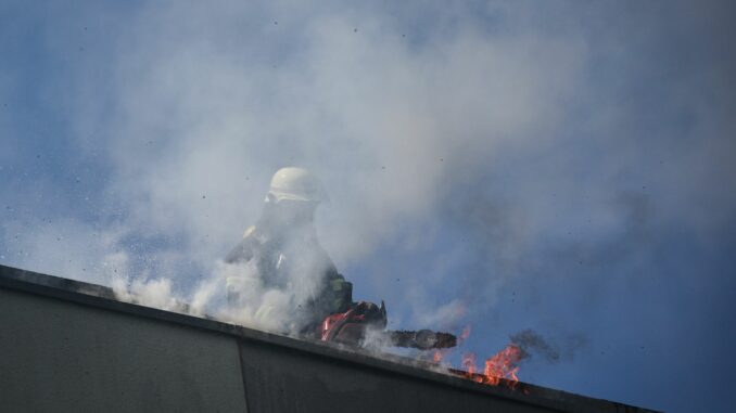 Flammen schlagen aus dem Dach eines viergeschossigen Wohnhauses.