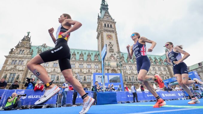 Triathlon-Teilnehmerinnen laufen am Hamburger Rathaus vorbei.