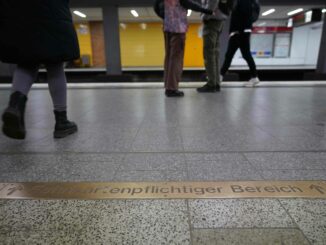 Fahrgäste gehen am Schriftzug «Fahrkartenpflichtiger Bereich» in einer U-Bahnstation vorbei.