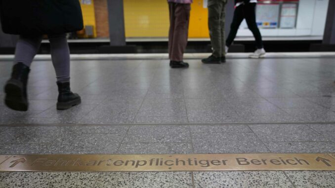 Fahrgäste gehen am Schriftzug «Fahrkartenpflichtiger Bereich» in einer U-Bahnstation vorbei.