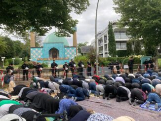 Die Polizei sichert die geschlossene Moschee, während Gläubige auf der Straße beten.