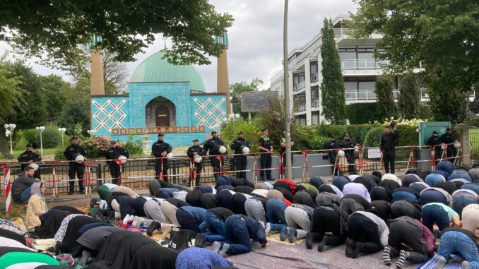 Die Polizei sichert die geschlossene Moschee, während Gläubige auf der Straße beten.