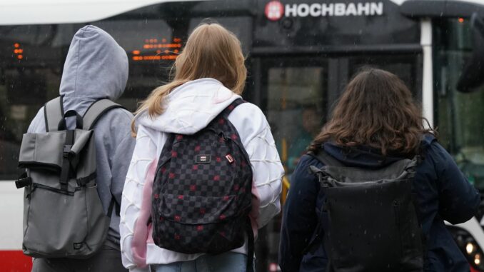 Zwei Schülerinnen und ein Schüler warten in Hamburg auf einen Bus. (Symbolbild)