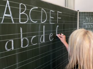 Eine Grundschullehrerin schreibt die ersten Buchstaben des Alphabets auf eine Schultafel. (Symbolfoto)