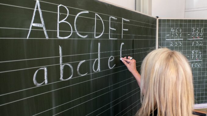 Eine Grundschullehrerin schreibt die ersten Buchstaben des Alphabets auf eine Schultafel. (Symbolfoto) 