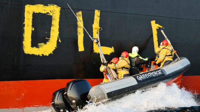 Aktivisten der Umweltorganisation Greenpeace malen den Schriftzug «Oil fuels war» auf den Rumpf eines Schiffes, das russisches Öl auf der Ostsee transportiert. (Archivbild)