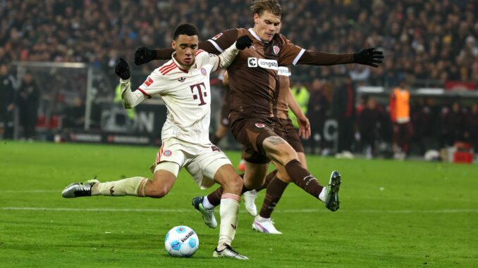 FC St. Paulis Abwehrspieler Eric Smith (r) verletzt sich beim Spiel gegen den FC Bayern.  