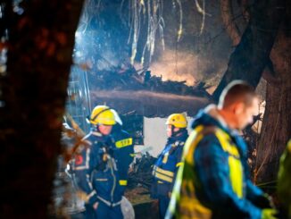 Reste des abgebrannten Hauses qualmen während den Nachlöscharbeiten hinter Einsatzkräften des THW.