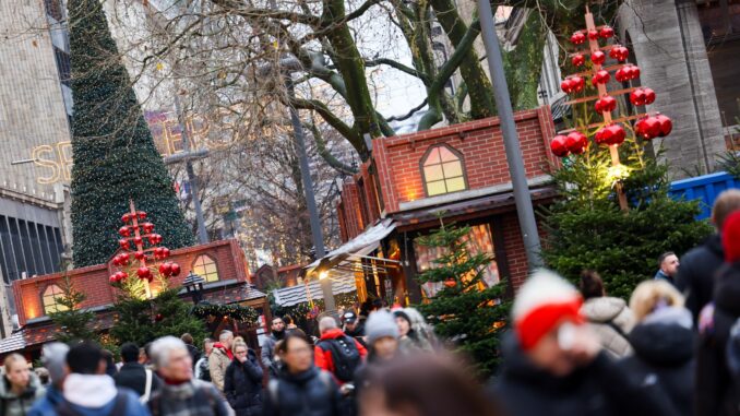 Passanten gehen mit Einkäufen durch die weihnachtliche Hamburger Innenstadt. 