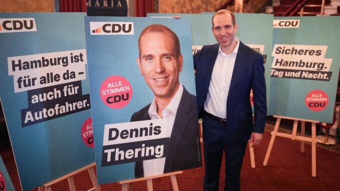 CDU-Spitzenkandidat Dennis Thering steht neben Wahlplakaten. 