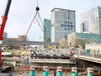 Ein großer Lastenkran hebt tonnenschwere Stahlträger zur Erneuerung der Berlinertordammbrücke  über der Straße Bürgerweide und den Bahngleisen ein.