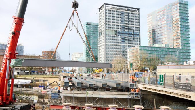 Ein großer Lastenkran hebt tonnenschwere Stahlträger zur Erneuerung der Berlinertordammbrücke  über der Straße Bürgerweide und den Bahngleisen ein. 