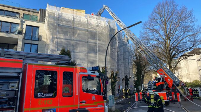 Über eine Drehleiter löschen Feuerwehrleute Glutnester auf dem Dach einer Baustelle ab.